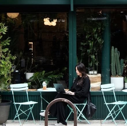 The green storefront of La La Laundry × Atelier on East 3rd Street, with mint bistro chairs